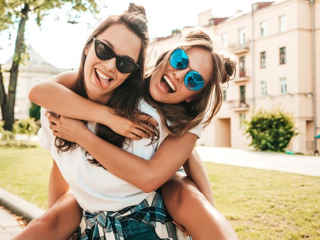 Zwei junge schöne lächelnde Hippie-Frau in trendiger weißer Sommer-T-Shirt-Kleidung
