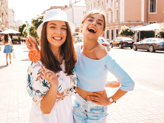 Zwei junge schöne lächelnde Hippie-Mädchen in der modischen Sommerkleidung und im Panama-Hut.