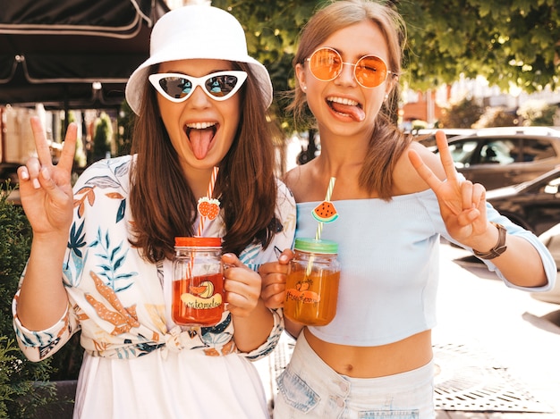 Zwei junge schöne lächelnde Hippie-Mädchen in der modischen Sommerkleidung und im Panama-Hut.