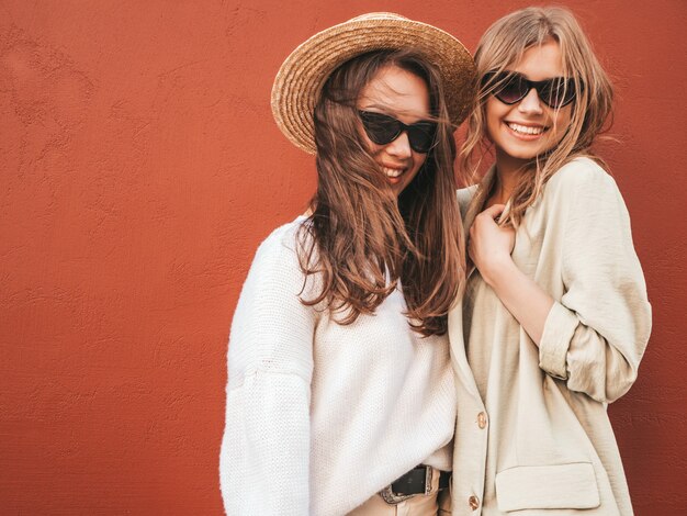 Zwei junge schöne lächelnde hipster-frau im trendigen weißen pullover und mantel