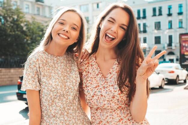 Zwei junge schöne lächelnde Hipster-Frauen in trendiger SommerkleidungSexy sorglose Frauen, die auf der Straße posieren Positive reine Modelle, die Spaß bei Sonnenuntergang haben, umarmen und verrückt werden Fröhlich und fröhlich