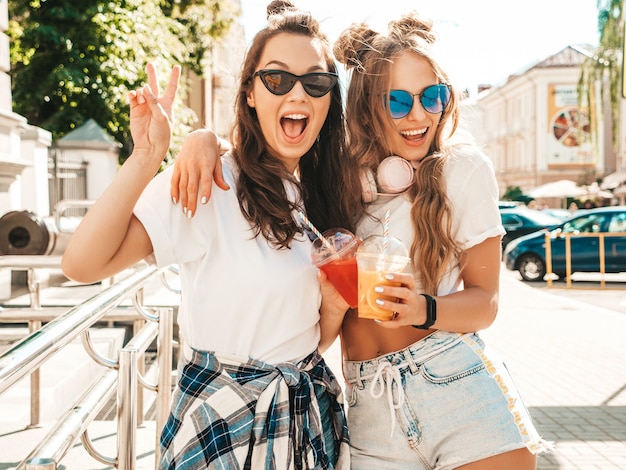 Zwei junge schöne lächelnde Hipster-Mädchen in trendiger Sommerkleidung