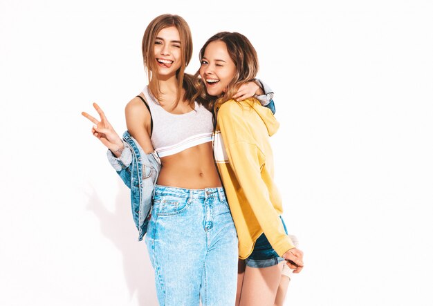 Zwei junge schöne lächelnde Mädchen in den modischen Sommerjeans kleidet. Sexy sorglose Frauen. Positive Vorbilder