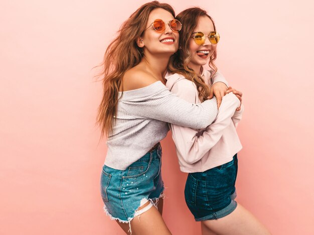 Zwei junge schöne lächelnde Mädchen in der modischen Sommerkleidung. Sexy sorglose Frauenaufstellung. Positive Models, die Spaß haben