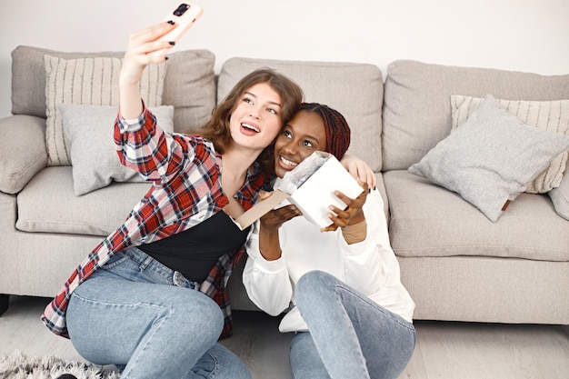 Zwei junge Teenager-Mädchen sitzen auf einem Boden in der Nähe des Trainers und machen ein Selfie
