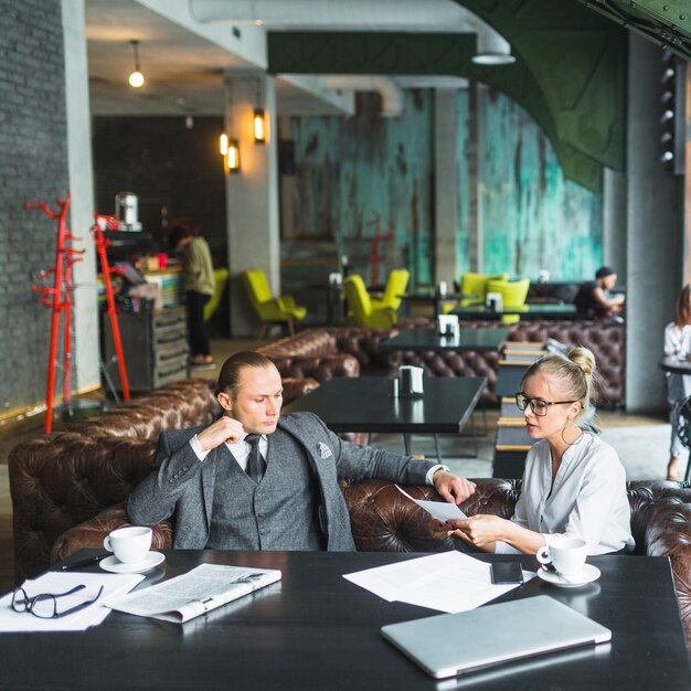 Zwei junge Wirtschaftler, die Dokument im Restaurant analysieren