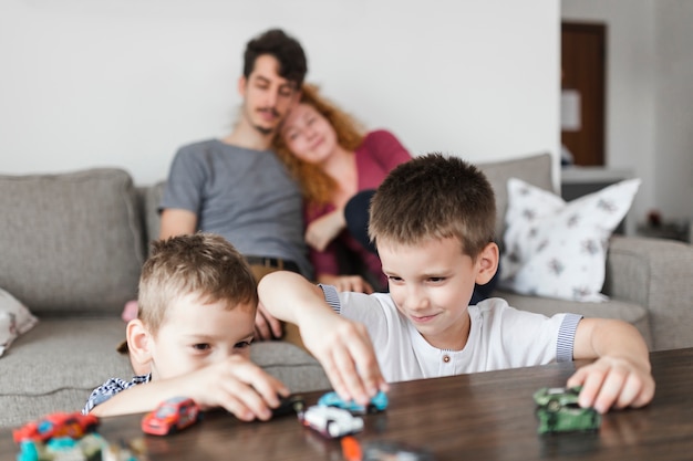 Zwei Jungen, die mit Auto spielen, spielt über hölzernem Schreibtisch