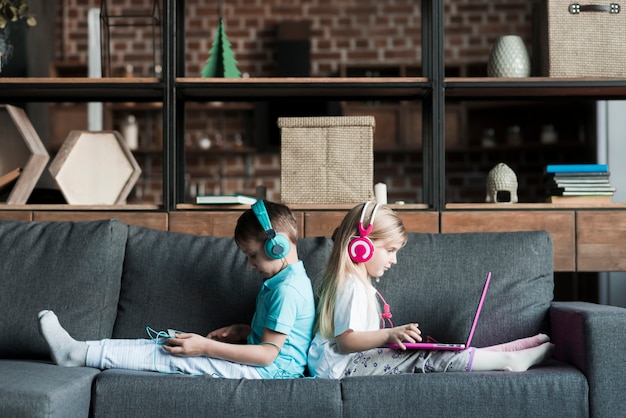 Zwei Kinder auf der Couch mit Laptop