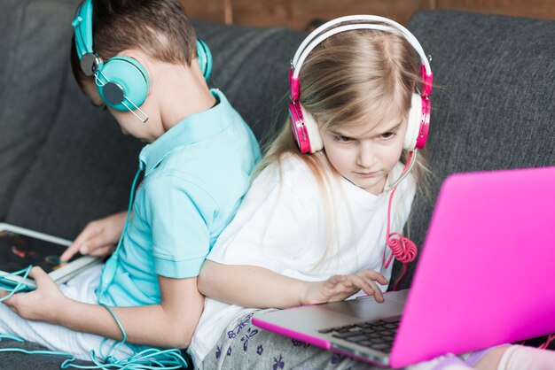 Zwei Kinder auf der Couch mit Laptop