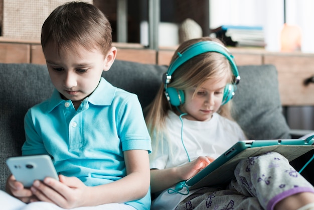 Zwei Kinder mit Tablet und Smartphone