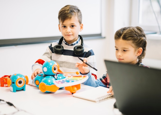 Zwei kleine Kinder, die mit digitalen Spielwaren im Klassenzimmer spielen