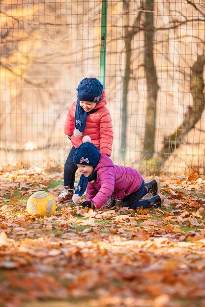 zwei kleine Mädchen, die im Herbstlaub spielen