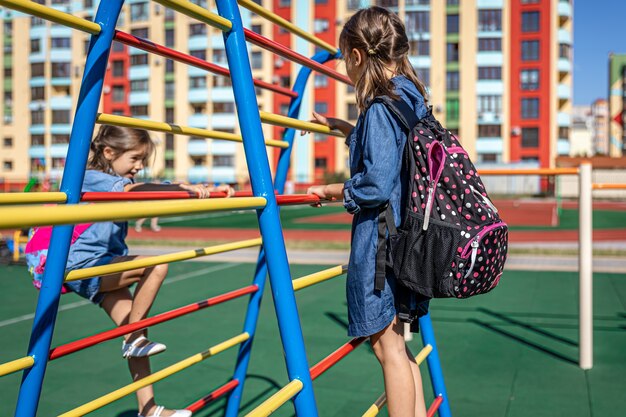 Zwei kleine Mädchen, Grundschüler, spielen nach der Schule auf dem Spielplatz.