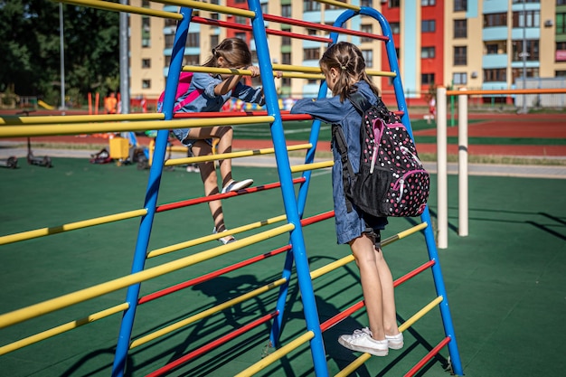 Zwei kleine Mädchen, Grundschüler, spielen nach der Schule auf dem Spielplatz.