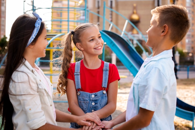 Zwei kleine Mädchen und Händchenhalten eines Jungen zusammen