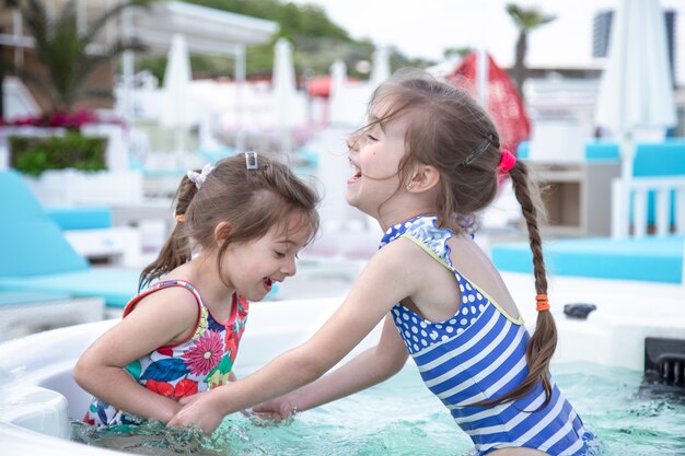 Zwei kleine süße Schwestern spielen im Pool. Familienwerte und Freundschaft.