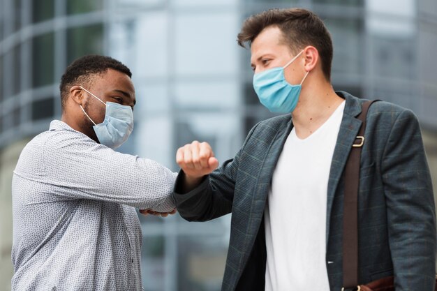 Zwei Kollegen berühren während einer Pandemie im Freien die Ellbogen