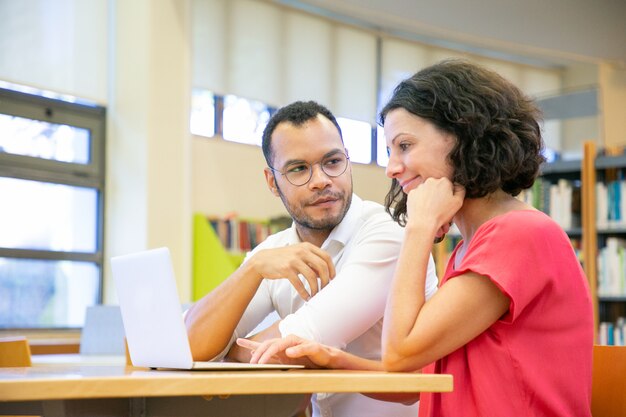 Zwei Kollegen, die an Darstellung in der Bibliothek arbeiten