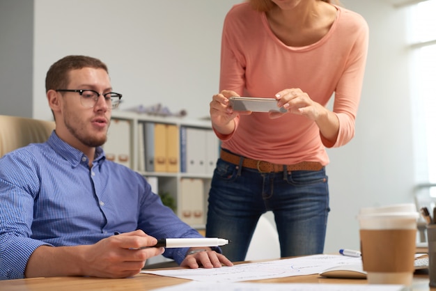 Zwei Kollegen fotografieren Ausdruckdokumente, an denen sie arbeiten