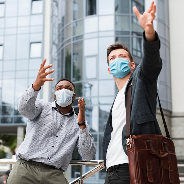Zwei Kollegen im Freien während der Pandemie tragen medizinische Masken