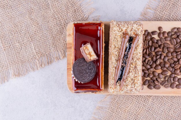 Zwei Kuchen und Kaffeebohnen auf Holzbrett. Foto in hoher Qualität