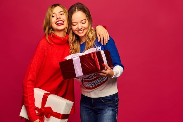 Zwei lächelnde schöne Frauen in stilvollen Pullovern mit großen Geschenkboxen
