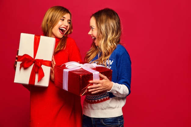 Zwei lächelnde schöne Frauen in stilvollen Pullovern mit großen Geschenkboxen