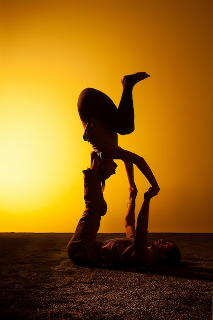 Zwei Leute, die Yoga im Sonnenuntergangslicht praktizieren