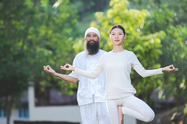 Zwei Leute im weißen Outfit, die Yoga in der Natur tun