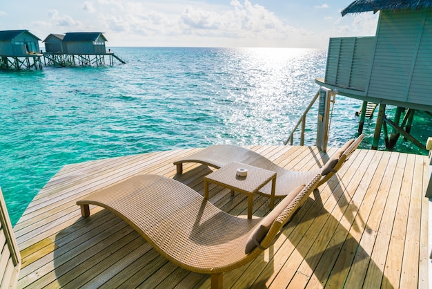 Zwei Liegestühle auf dem Holzboden im Wasser Villa Sonnenuntergang Zeit, Malediven Insel