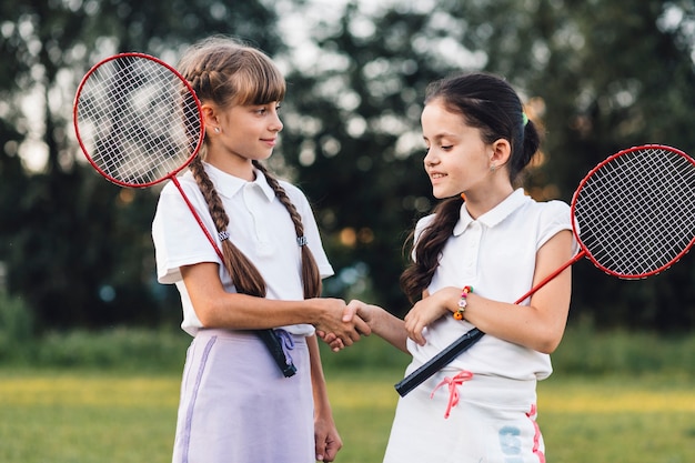 Zwei Mädchen, die Badminton rütteln Hände mit einander halten