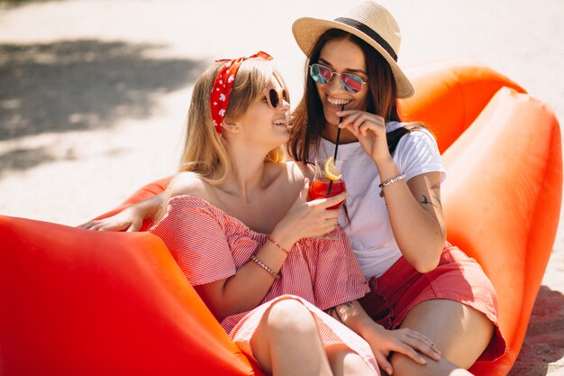 Zwei Mädchen, die Cocktails am Strand trinken