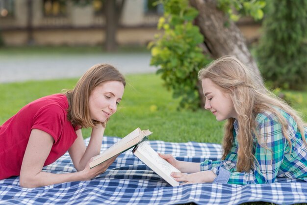 Zwei Mädchen, die draußen auf Picknickdecke studieren