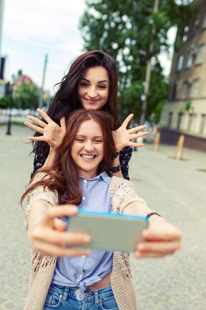 Zwei Mädchen, die lustiges selfie auf der Straße, Spaß zusammen habend machen