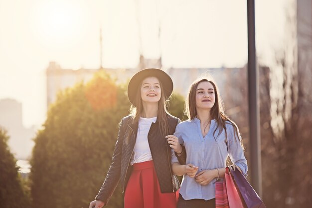 Zwei Mädchen, die mit dem Einkaufen auf Stadtstraßen gehen