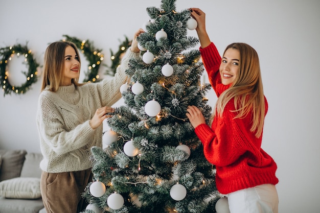 Zwei mädchen, die weihnachtsbaum schmücken