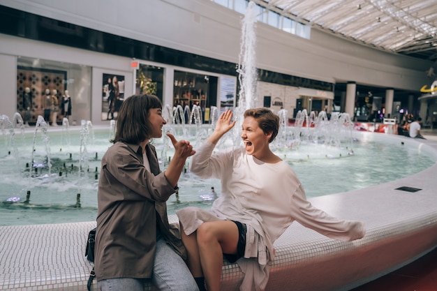 Zwei mädchen haben spaß im einkaufszentrum neben einem brunnen