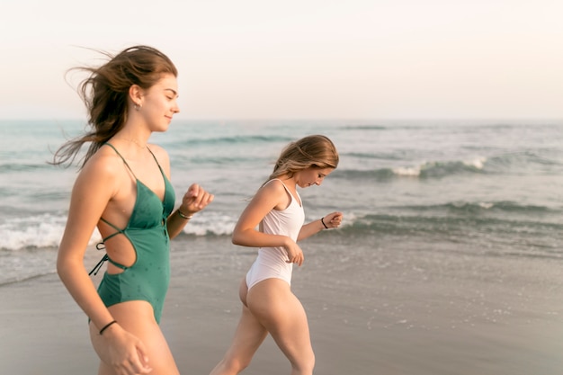 Zwei Mädchen im Bikini gehend nahe dem Meer am Strand