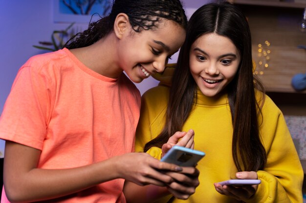 Zwei Mädchen im Teenageralter, die zu Hause auf Smartphones SMS schreiben