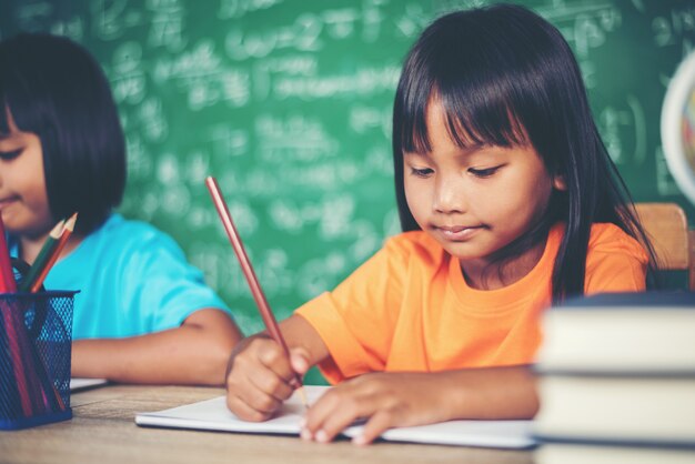 Zwei Mädchen mit dem Zeichenstift, der an der Lektion im Klassenzimmer zeichnet