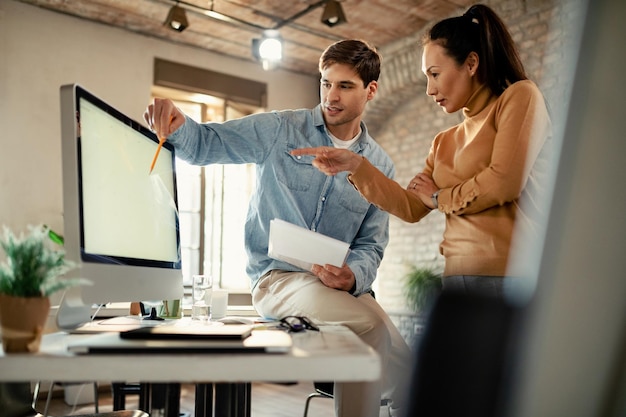 Zwei Mitarbeiter, die zusammenarbeiten, während sie Computer benutzen und im Büro arbeiten