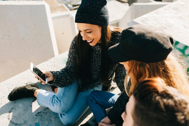 Zwei moderne Mädchen, die Smartphone betrachten