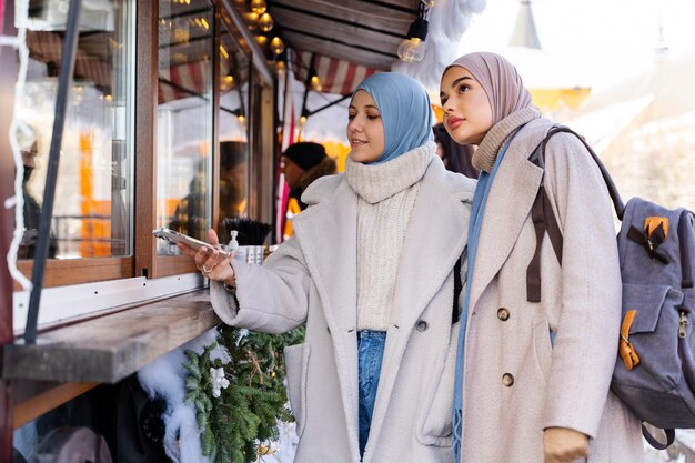 Zwei muslimische Frauen besuchen auf Reisen eine Konditorei