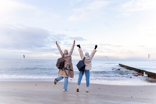 Zwei muslimische Freundinnen, die auf Reisen am Strand spazieren gehen