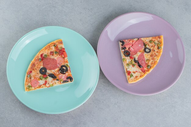 Zwei Platten mit Pizzastücken auf Marmor