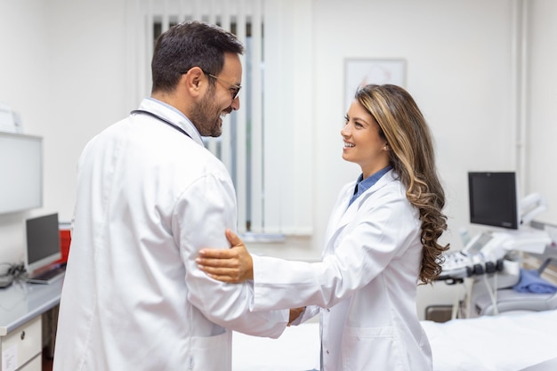 Zwei professionelle selbstbewusste Ärzte schütteln sich die Hände, während sie in der Klinik stehen