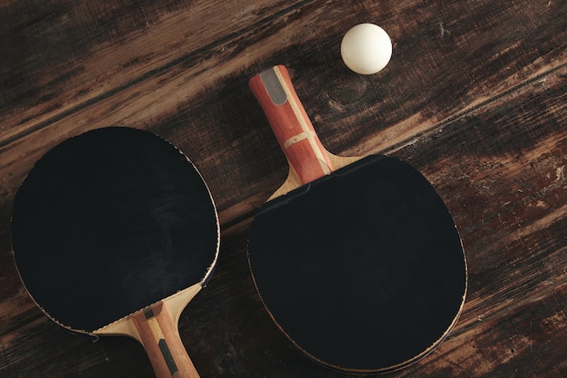 Zwei professionelle Tischtennisraketen, die auf Weinlesetisch liegen.