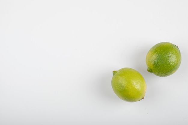 Zwei reife Limettenfrüchte lokalisiert auf weißem Hintergrund.