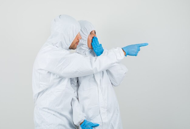 Zwei Ärzte in Schutzanzügen, Handschuhe, die etwas Überraschendes betrachten