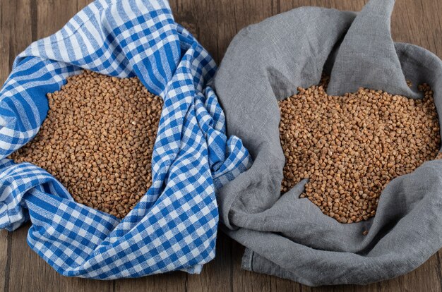 Zwei Sackleinen roher Buchweizen auf Holztisch